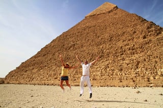 Couple Jumping With Joy At Pyramids In Egypt