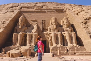 White Woman Tourist In Front Of The Colossal Statues Of Ramesses Ii Seated On A Throne Near The