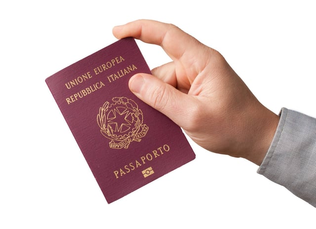 Hand hält einen italienischen Reisepass auf weißem Hintergrund